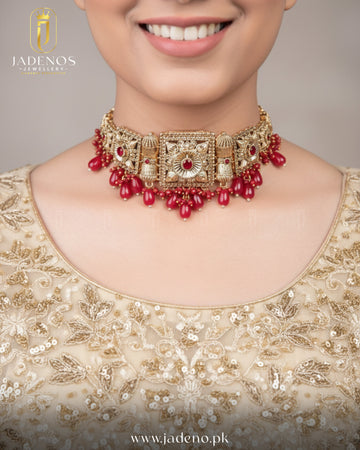 Statement look featuring Noor-e-Ronaq choker set with tika, gold choker with red stones and bead drops.