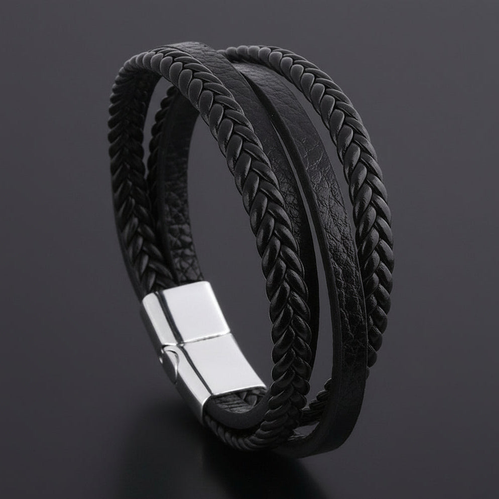 Black braided leather bracelet with a silver clasp on a dark background