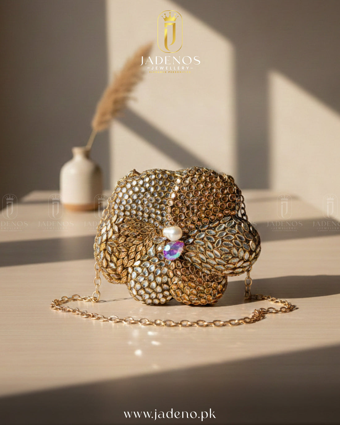 The Scarlet Core Clutch with gold floral design, crystal embellishments, pearl center, and delicate chain strap in soft lighting.